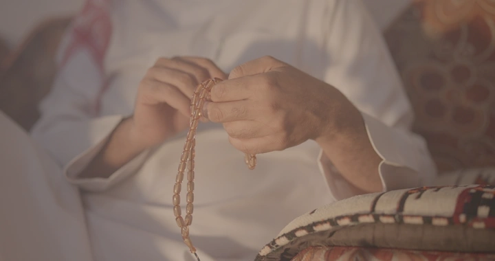 رجل يمسك سبحة في يده داخل منزل، لقطة مقربة.