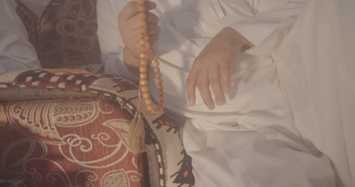 يد تحمل سبحة في جلسة تقليدية، لقطة مقربة.