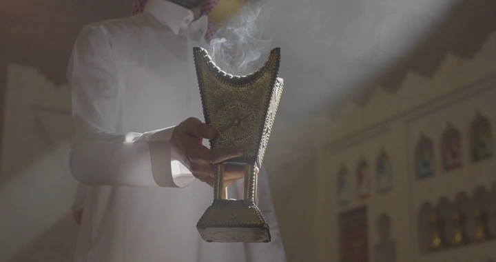 رجل يحمل مبخرة في غرفة مضاءة بأشعة الشمس، لقطة مقربة.