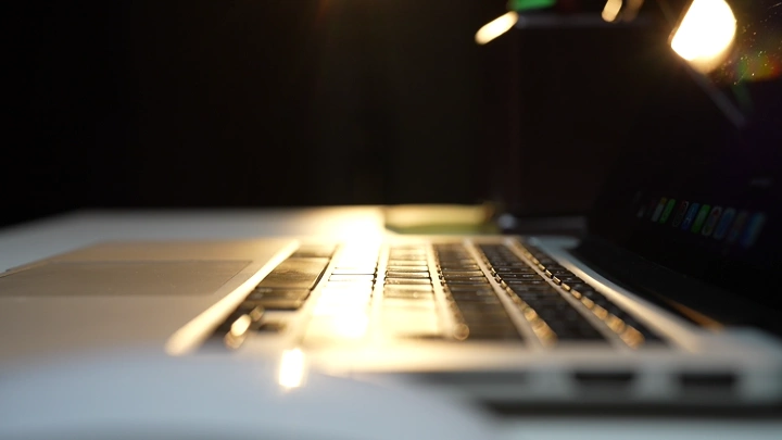 رجل يدخل البيانات على لوحة المفاتيح في مكتب مضاء بمصباح، لقطة جانبية.