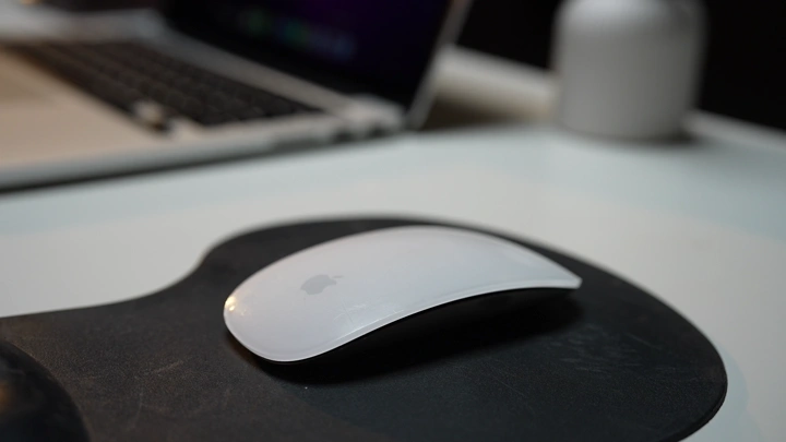 شاب يعمل على ماوس على مكتب بجانب لابتوب، لقطة قريبة.