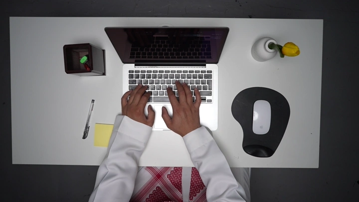 رجل يعمل على لابتوب في مكتب، لقطة من الأعلى.