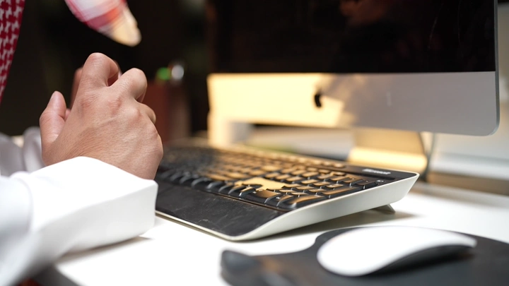 يدين على لوحة مفاتيح جهاز كمبيوتر في مكتب، لقطة مقربة.