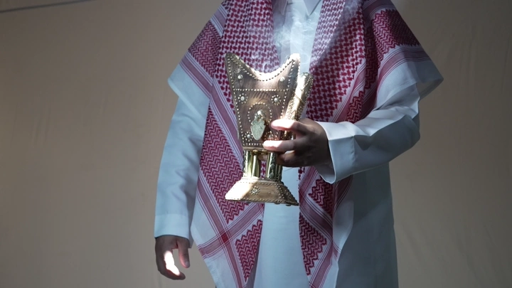 رجل يرتدي الثوب والغترة يحمل مبخرة تقليدية، لقطة قريبة.