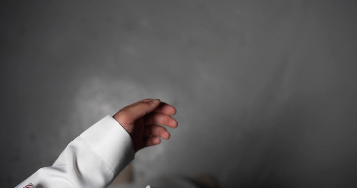 رجل  يعد النقود  ثوب أبيض على خلفية رمادية، لقطة مقربة.