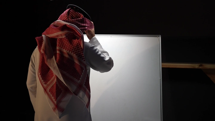 رجل سعودي يكتب على سبورة ، لقطة جانبية.