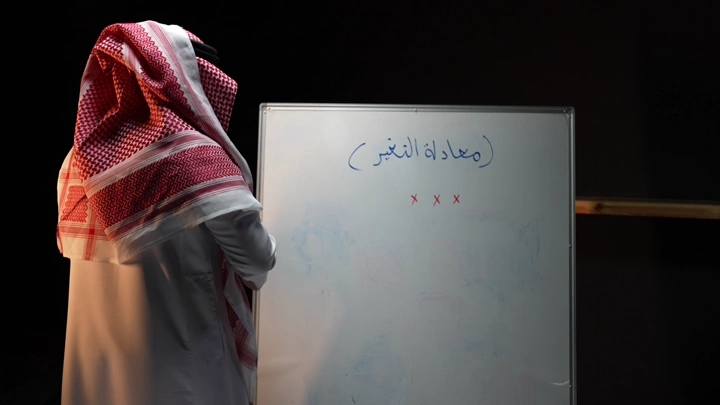 رجل سعودي يكتب على سبورة ، لقطة جانبية.