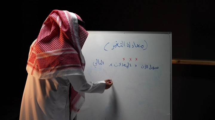 رجل سعودي يكتب على سبورة ، لقطة جانبية.