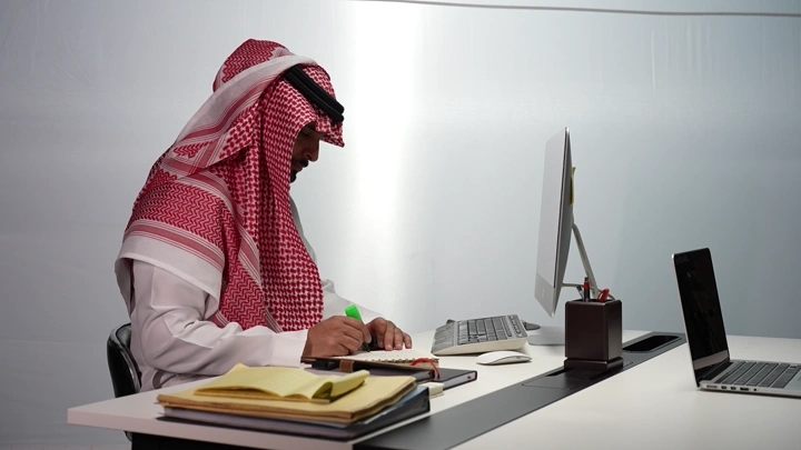 رجل سعودي يعمل في مكتب حديث، لقطة جانبية.