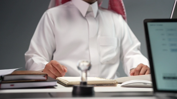 رجل سعودي في مكتب مع كمبيوتر محمول، لقطة داخلية.