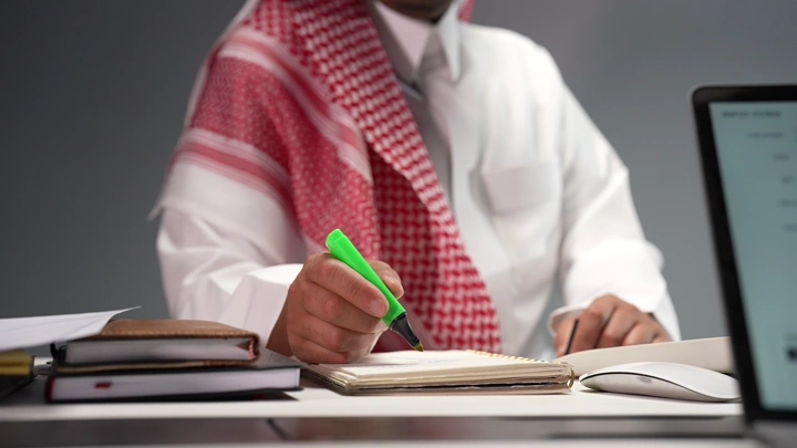 رجل سعودي يدرس في مكتب، لقطة مقربة.