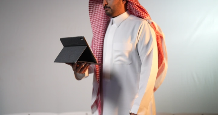 رجل سعودي يحمل جهاز آيباد في استوديو، لقطة جانبية.