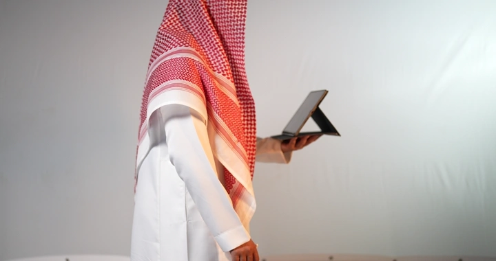 رجل سعودي يحمل جهاز آيباد وينقر على الشاشة، لقطة جانبية في استوديو.