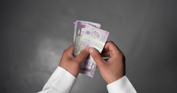 رجل يعد النقود السعودية في يده، لقطة مقربة.