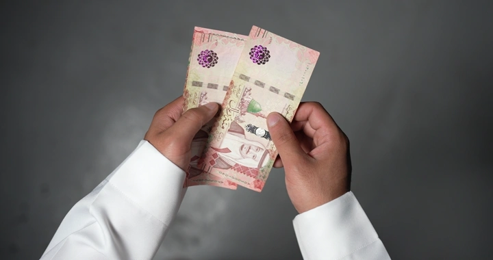 رجل سعودي يعد النقود بيديه، لقطة مقربة.