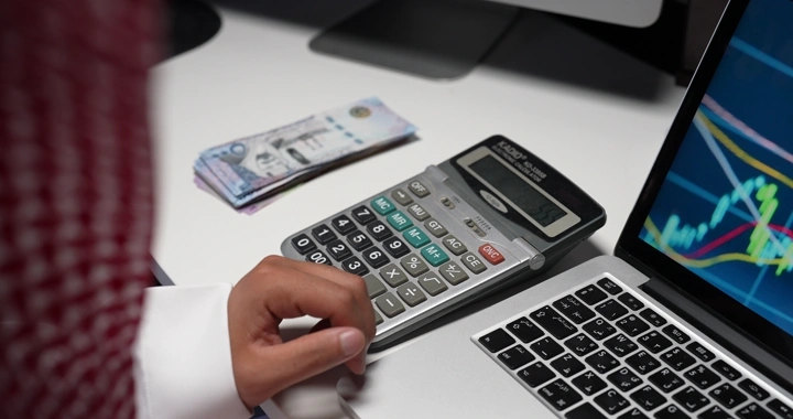 رجل سعودي يحسب المال على مكتب، لقطة مقربة.