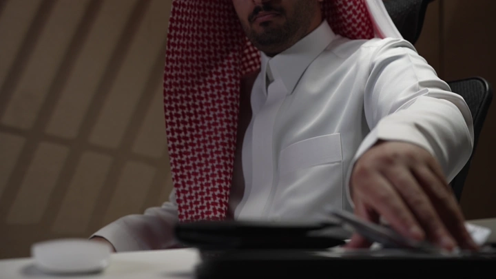 رجل سعودي في مكتب مع نقود على الطاولة، لقطة قريبة.