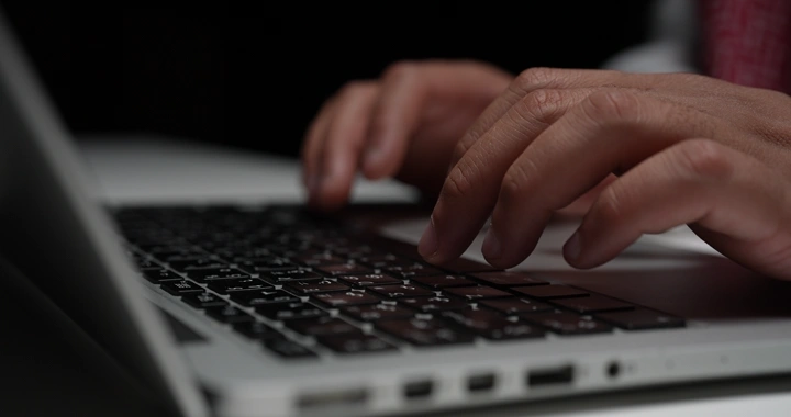 يد تكتب على لوحة مفاتيح لابتوب، لقطة مقربة.
