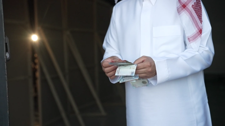 رجل سعودي يعد النقود في مكان داخلي، لقطة قريبة.