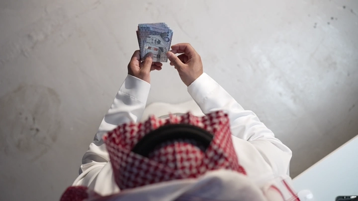 رجل يرتدي ثوب يعد النقود في الداخل، لقطة من الأعلى.