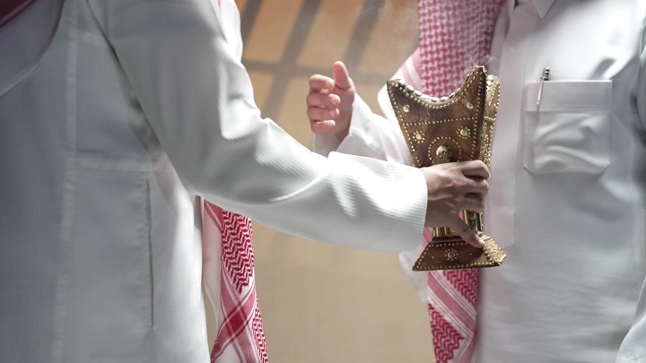 رجلان يرتديان الثوب السعودي يتبادلان مبخرة، لقطة قريبة.