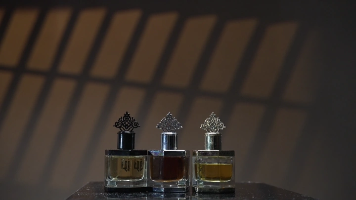 رجل يختار من زجاجات العطور على طاولة بإضاءة خافتة، لقطة ثابتة.