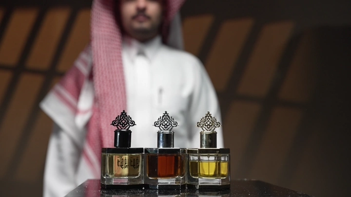 زجاجات عطر على طاولة مع رجل في الخلفية، لقطة قريبة.