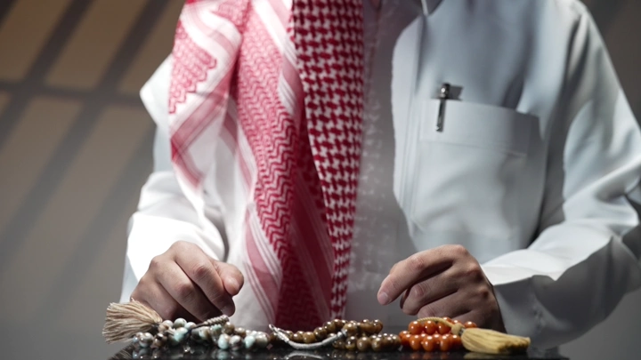 رجل سعودي يرتدي الثوب والشماغ يمسك سبحة، لقطة مقربة.