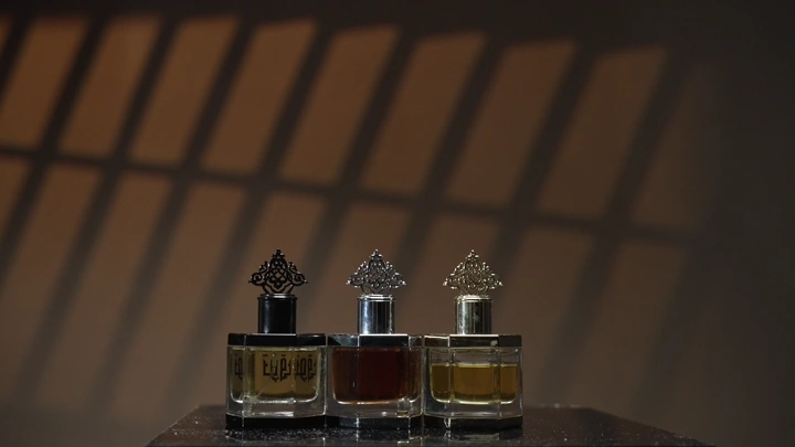 رجل يختار من زجاجات عطرو على طاولة بإضاءة خافتة، لقطة قريبة.