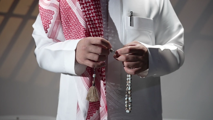 رجل سعودي يحمل سبحة في يده، لقطة مقربة.