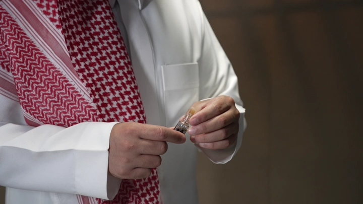 رجل يحمل زجاجة دهن عود، لقطة مقربة.