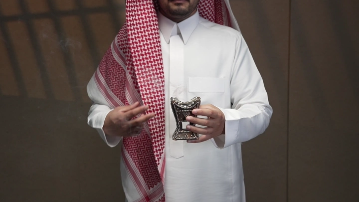 رجل سعودي يحمل مبخرة ويبخر شماغه ، لقطة داخلية.