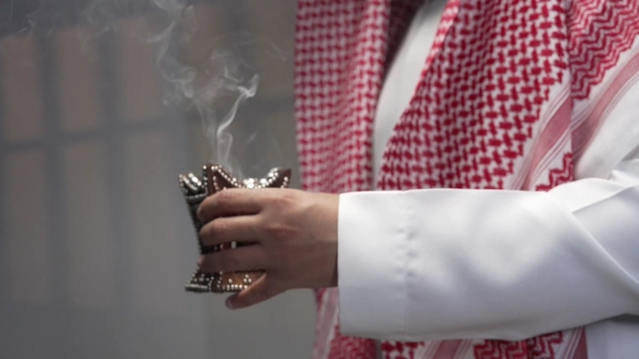 رجل يرتدي الزي السعودي يقدم البخور، لقطة مقربة.