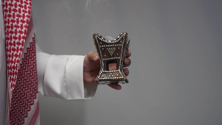 رجل يرتدي ثوبًا سعوديًا يحمل مبخرة، لقطة مقربة.