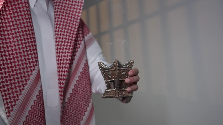 رجل سعودي يحمل مبخرة تقليدية في غرفة، لقطة مقربة.