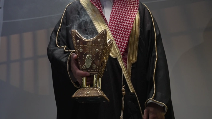 رجل سعودي يحمل مبخرة تقليدية، تصوير داخلي.