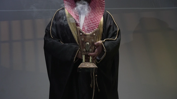 رجل سعودي يحمل مبخرة تقليدية في غرفة، لقطة قريبة.