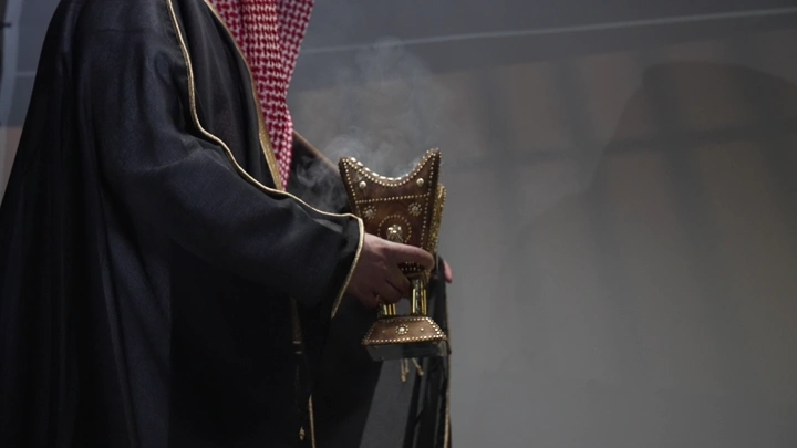 رجل يرتدي البشت السعودي يحمل مبخرة، لقطة قريبة.