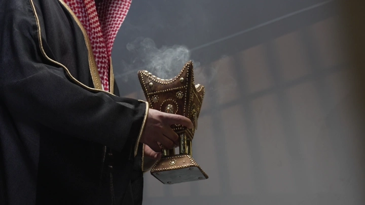 رجل سعودي يرتدي بشت يحمل مبخرة، لقطة قريبة.