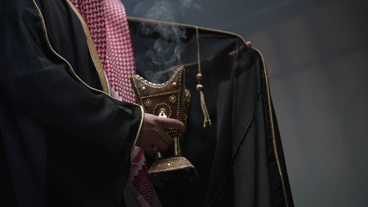 رجل سعودي يرتدي بشت يحمل مبخرة، لقطة مقربة.