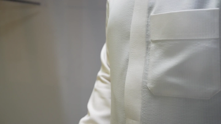 رجل يرتدي ثوبًا أبيض في غرفة مضاءة، لقطة قريبة.
