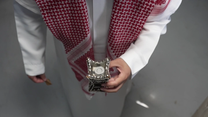 رجل سعودي يحمل مبخرة في يده، لقطة من الأعلى.