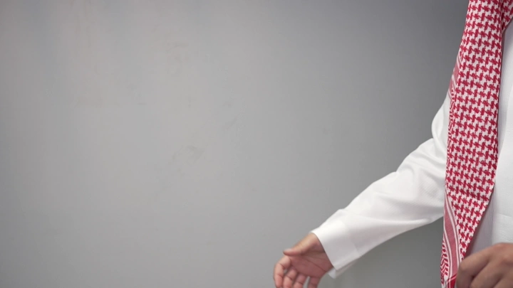 رجل يرتدي ثوبًا وغترة يستعد للمصافحة، لقطة مقربة.