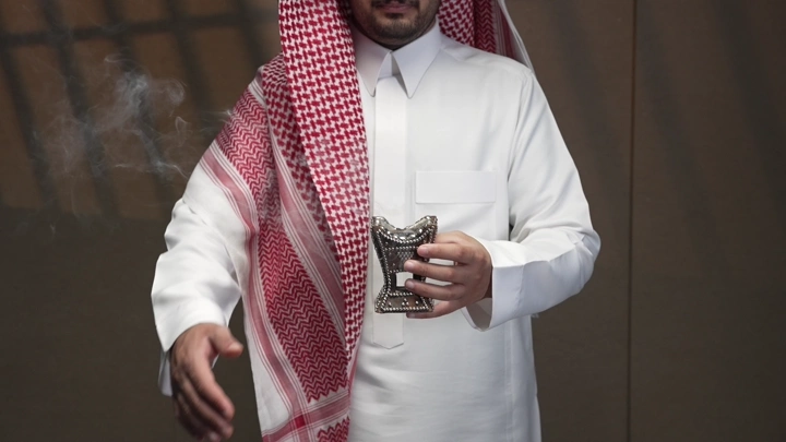 رجل سعودي يرتدي الثوب والشماغ يتبخر داخل غرفة، لقطة مقربة.