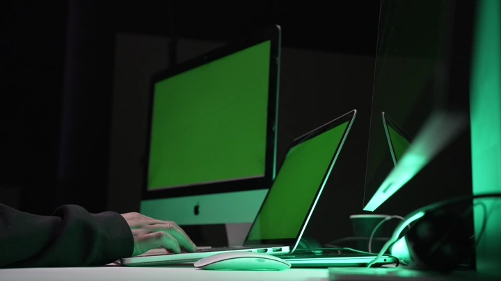 شخص يعمل على أجهزة كمبيوتر بشاشات كروما خضراء، لقطة داخلية.