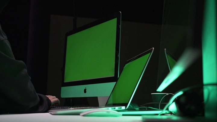 رجل جالس أمام شاشات كروما خضراء في غرفة مظلمة، لقطة داخلية.