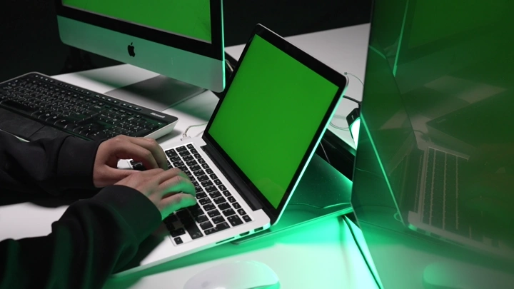 شخص يعمل على حاسوب محمول بشاشة كروما خضراء، لقطة داخلية.