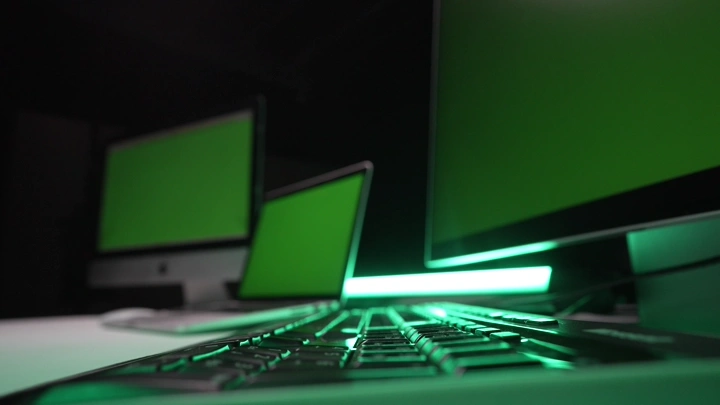 لوحة مفاتيح مع شاشات كروما خضراء في غرفة مظلمة، لقطة قريبة.