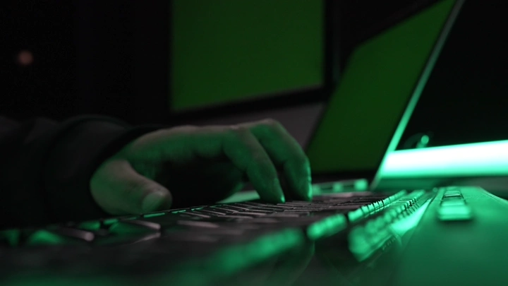 يد تكتب على لوحة مفاتيح بإضاءة خضراء، لقطة قريبة.