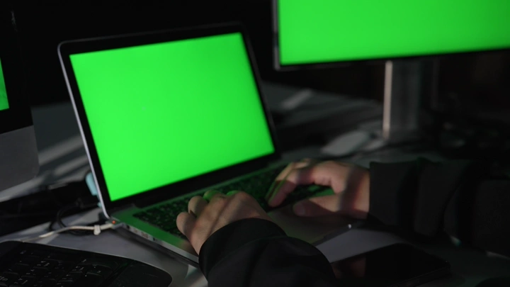 رجل يعمل على حاسوب بشاشة كروما خضراء، لقطة قريبة.